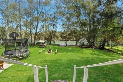 The beautiful view out to the water over the lush lawn, fire pit, trampoline and private jetty