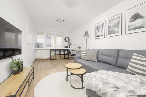 A bright living room with a large gray sofa, a round coffee table, and framed artwork on the walls, creating a stylish and cozy atmosphere.

