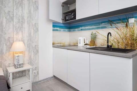 A modern kitchenette with sleek white cabinets, a blue LED backsplash, and a compact yet functional design.