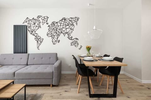 A stylish living and dining area featuring a gray sofa, a wooden dining table, and a world map wall decoration adding a modern touch.

