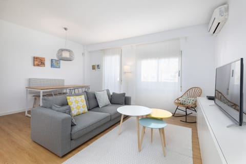 Large living room with sofa, practical rectangular dining table, HD TV, with access to an outside balcony.
