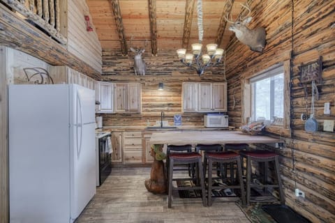 Fully equipped kitchen with island seating, log cabin finishes, and open sightlines to the living space.