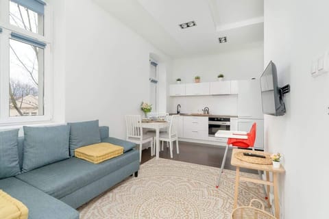 A cozy living space featuring a blue sofa, a white dining table, and minimalist decor, creating a bright and inviting atmosphere.

