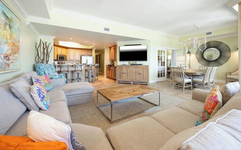 This inviting living space features a large sectional sofa, a mounted TV, and a stylish dining table, perfect for gatherings