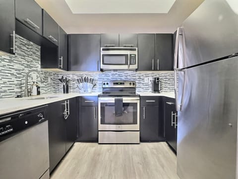 Modern kitchen with sleek stainless steel appliances and neatly arranged utensils, perfect for effortless cooking during your short-term rental stay.