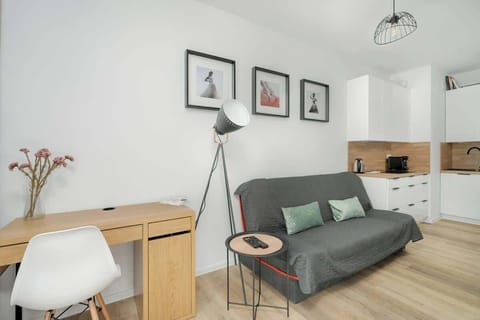 A modern living area featuring a gray sofa, a wooden desk, and stylish black-and-white framed artwork, creating a cozy yet sophisticated atmosphere.

