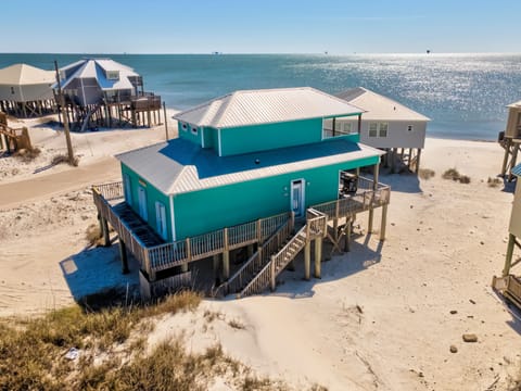 Beachfront vacation home elevated on stilts with direct beach access and stunning Gulf waters backdrop.
