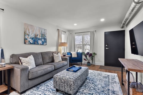 Unwind on the plush gray sofa while natural light streams through your windows, creating the perfect spot for relaxation.