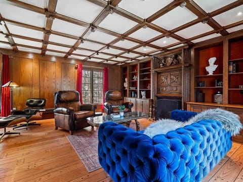 Elegant living room w/ tufted blue sofa, wood built-ins & coffered ceiling for a refined lounge space.