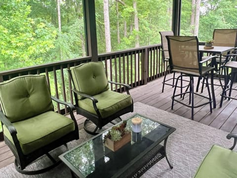 Screened in porch with seating area, dining table for 4, TV, and gas fireplace