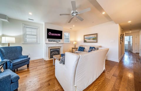 Bright coastal living room with fireplace and TV