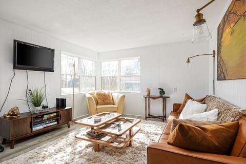 Bright living room w/ large windows, plush leather couch & warm wood accents for relaxed gatherings.