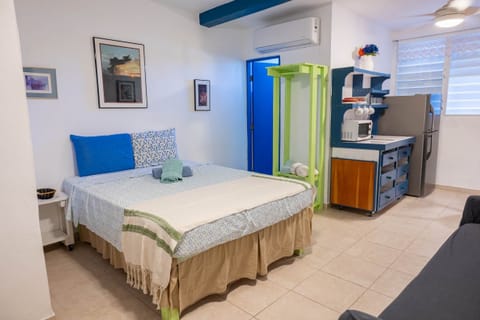 Queen bed in a room with fans and air conditioner.