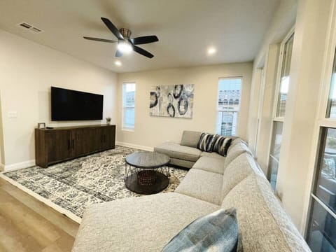 Downstairs living space features a large sectional, 65" Samsung smart TV, and a ceiling fan. 