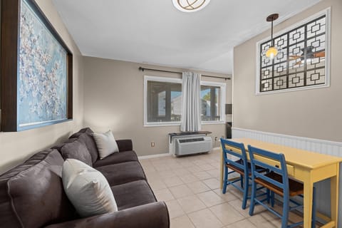 Sleek studio vibes: tile floors, cozy sofa, and dual-purpose dining/work table.