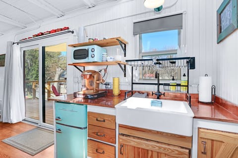 The kitchenette features a large farmhouse style sink, a mini fridge, and a little microwave