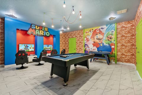 Experience a lively game room with a stunning Super Mario mural that invites fun. The cheerful blue and red walls enhance the stylish pool table, making it an ideal space for friendly competitions and joyful moments.