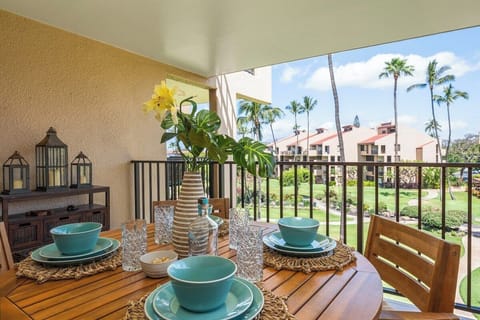 Furnished garden‑view lanai with teak dining table for four and tropical breezes.