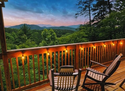 Cozy mountain-view deck with string lights and serene sunset scenery.