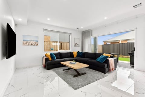 Kick back in this bright and stylish lounge room featuring a huge comfy couch, smart TV, and sliding doors that open out to the backyard for easy indoor-outdoor living