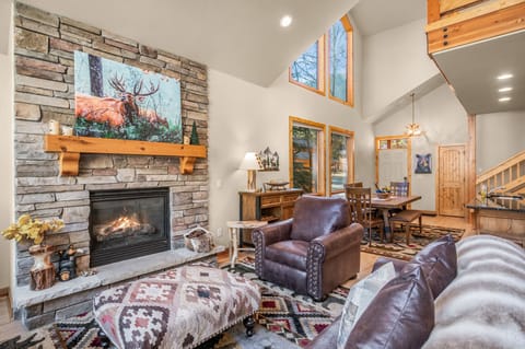 Open living, dining and kitchen space. Gas fireplace surrounded by comfortable sofa seating and charming mountain decor.