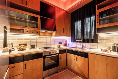 Modern L-shaped kitchen with wood cabinets, sleek appliances, and warm lighting.