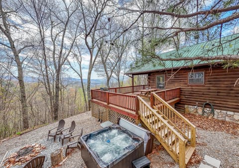 Exterior view of the Dream Circle log cabin featuring a wooden access ramp and covered deck surrounded by wooded mountain scenery near Bryson City, NC. This Smoky Mountain cabin offers convenient one-level access in a private forest setting.