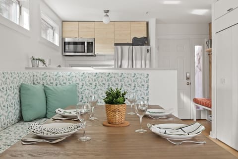 - Kitchen with stainless steel appliances and dining table seating   - Vacation rental dining space styled with modern table settings   - Airbnb listing offers open concept design with bright interiors
