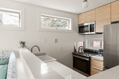 - Modern kitchen with stainless steel appliances and bright windows   - Airbnb rental includes microwave oven and electric stove for guests   - Vacation stay offers fully equipped kitchen with natural light