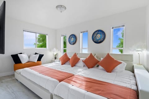 🛏️ Spacious Master Suite with panoramic windows & natural light! Sleeps 8 comfortably with premium linens & coral accents. Modern coastal design meets luxury comfort. Part of our Hollywood Beach villa - 3min to beach, hot tub & game room included!