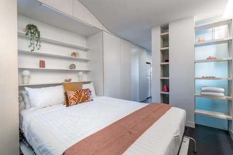 Rest in a serene, minimalist sanctuary featuring crisp white linens and warm timber accents.