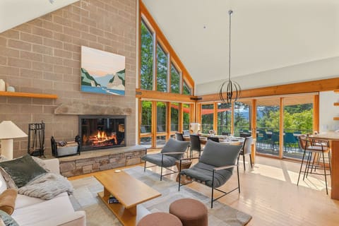 Gather in the sunlit great room, where soaring windows frame the forest and the fireplace warms every moment.