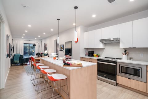 The fully equipped modern kitchen features culinary essentials, stainless steel appliances, and island bar seating.