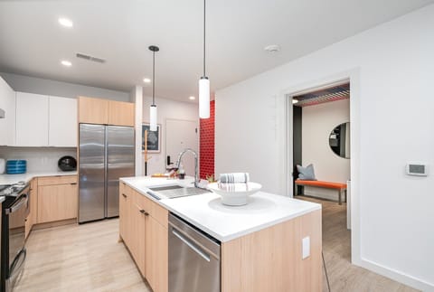 The fully equipped modern kitchen features culinary essentials, stainless steel appliances, and island bar seating.