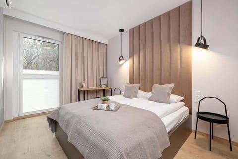 A cozy bedroom with a large double bed, soft beige tones, and warm lighting creating a relaxing atmosphere.