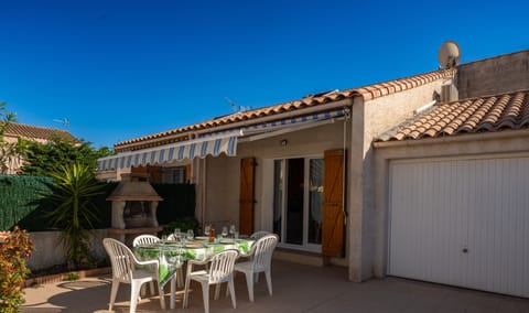 Terrace with garden furniture, charcoal barbecue and awning