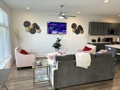 Stylish open-concept living area with modern decor, kitchen, and smart TV.