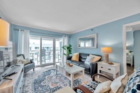 Bright coastal living area w/ comfy seating & sliding doors opening to the balcony.