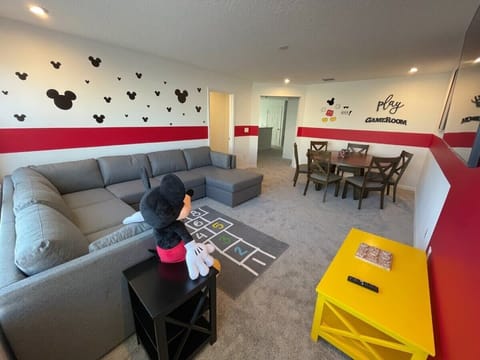 Enjoy family fun in this Mickey Mouse-themed game room with cozy seating, playful decor, and ample space for gatherings.
