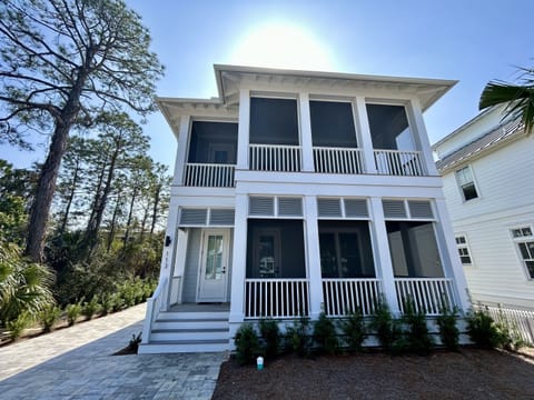 Beautiful two-story coastal home nestled among mature trees, featuring classic white architecture with wraparound porches and modern comfort.