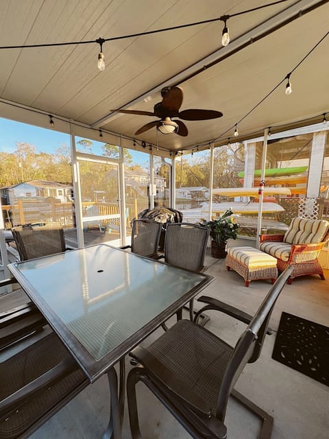 Large out door screened Lanai with Grill, outdoor chairs, dinning, overhead fan, and string lights.