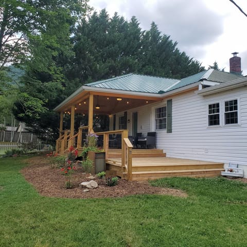 Front view of Bailey Hot Springs In Hot Springs, NC, surrounded by lush mountain scenery. Cozy mountain cabin with spacious front porch and year-round mountain views