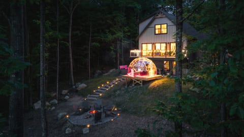 A serene backyard at night with an all-season dome, fire pit, and hot tub.