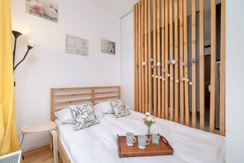 A modern bedroom with a wooden partition, a cozy double bed, and soft lighting, creating a warm and stylish ambiance.

