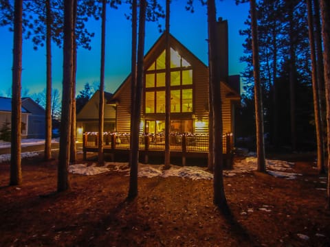 Cabin glowing at night with view of front deck