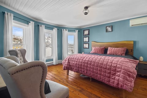 Unwind in style—where comfort meets charm. Spacious king bedroom with a queen bed, surrounded by natural light. 