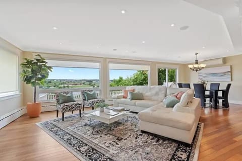 
A spacious living room with a cream sofa, patterned rug, and large windows showcasing a scenic view