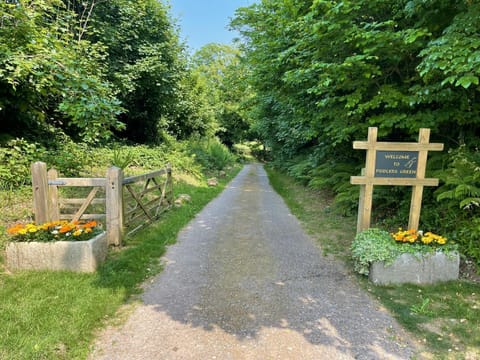 Entrance to Fiddlers Green, gravel driveway, entrance gate and stone planters with flowers