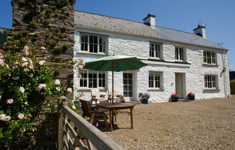 Front of the cottage with garden, chairs and parasol