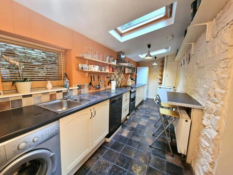 Kitchen with cooker, washing machine, dishwasher, kettle, toaster, breakfast bar, shelving